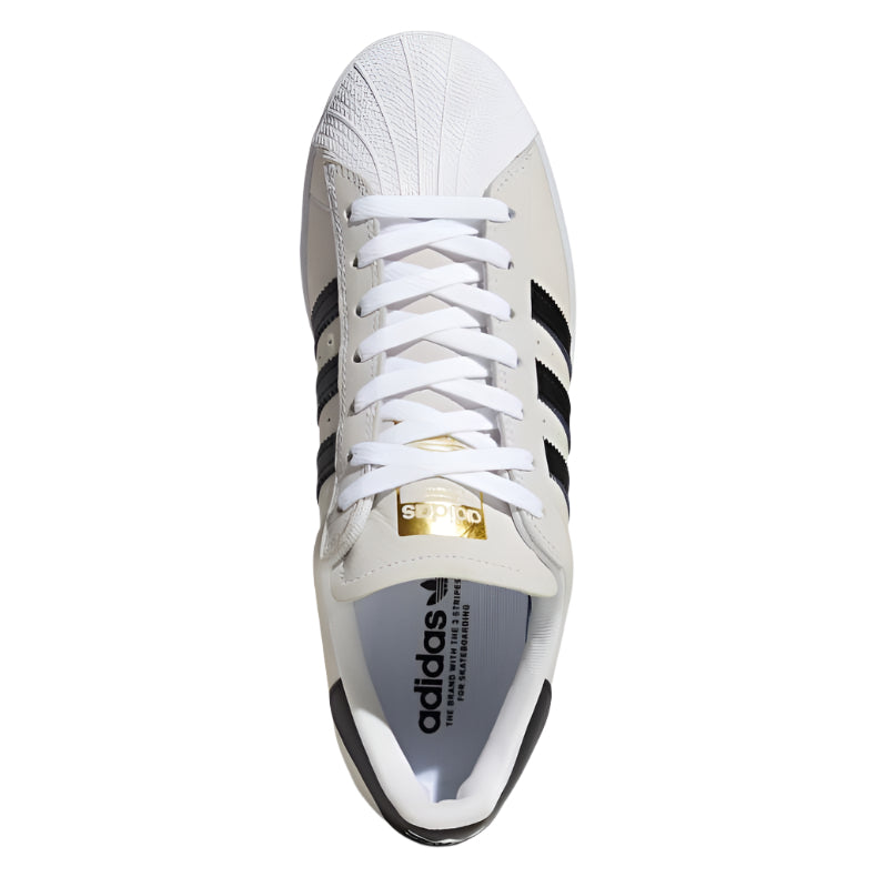 Adidas Superstar ADV, valkoinen/musta, ikonisella shell toe -designilla ja kultafolioyksityiskohdilla.