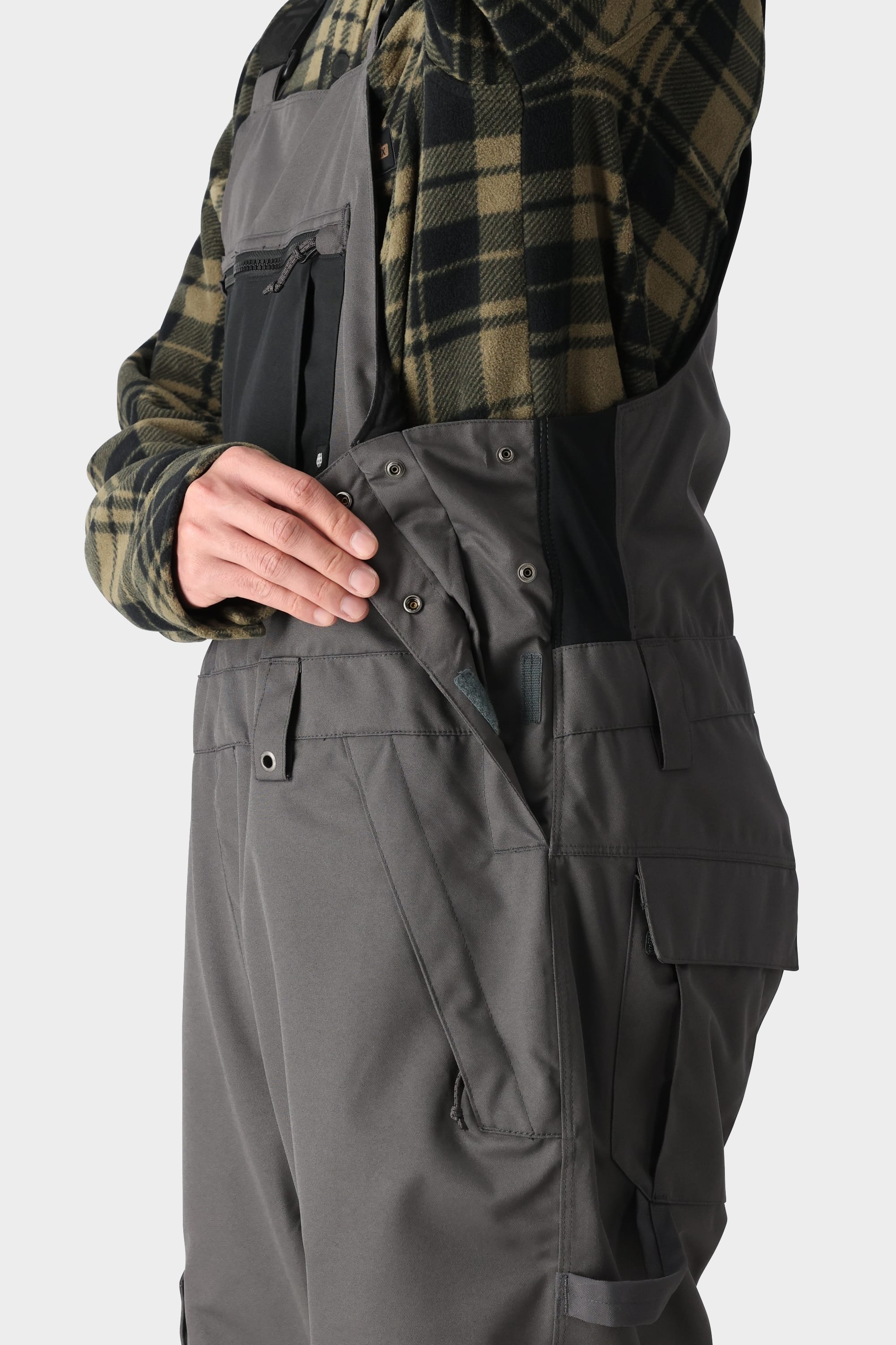 Insulated bib with side gusset, adjustable straps, and pockets for winter sports.