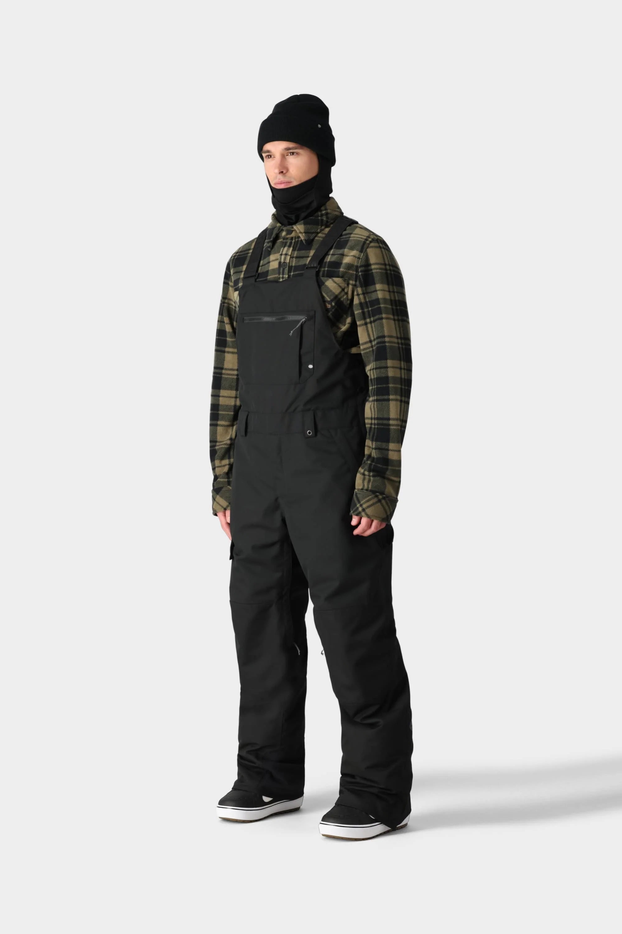 Man wearing Hot Lap Insulated BIB in black with green plaid shirt, showcasing cold-weather tech and style.